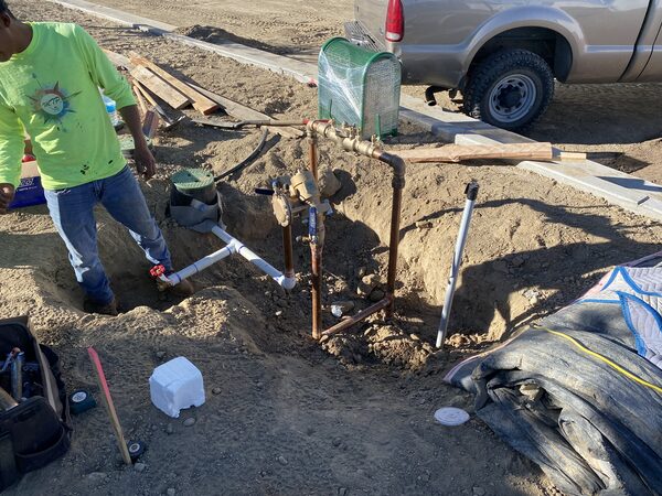 Irrigation backflow assembly and copper piping being installed in an open trench on a commercial site