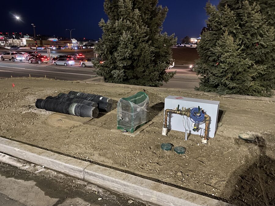 Backflow enclosure and coiled drainage pipe at a commercial site at night